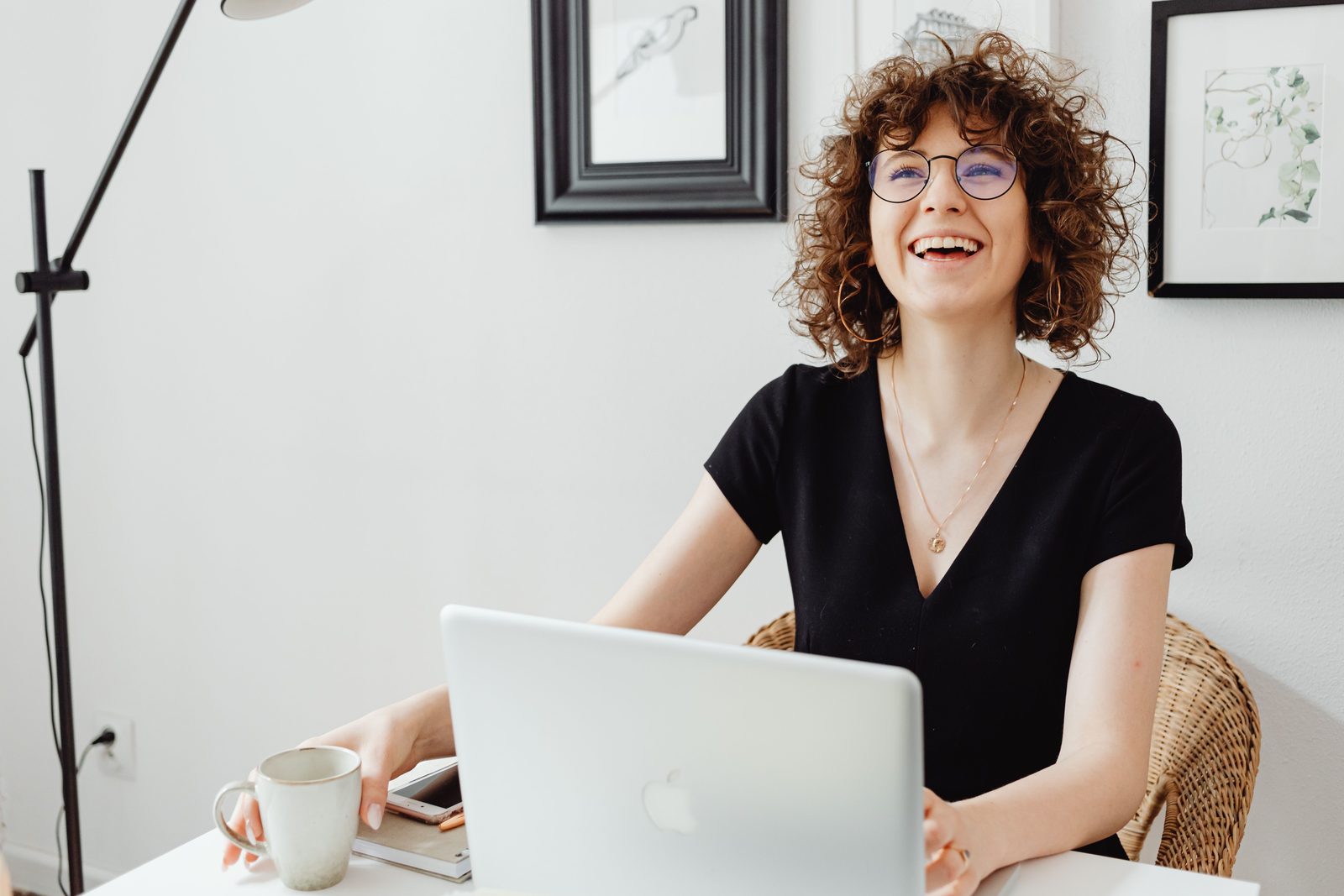 A woman laughing at her desk while working, supported by ADHD therapy