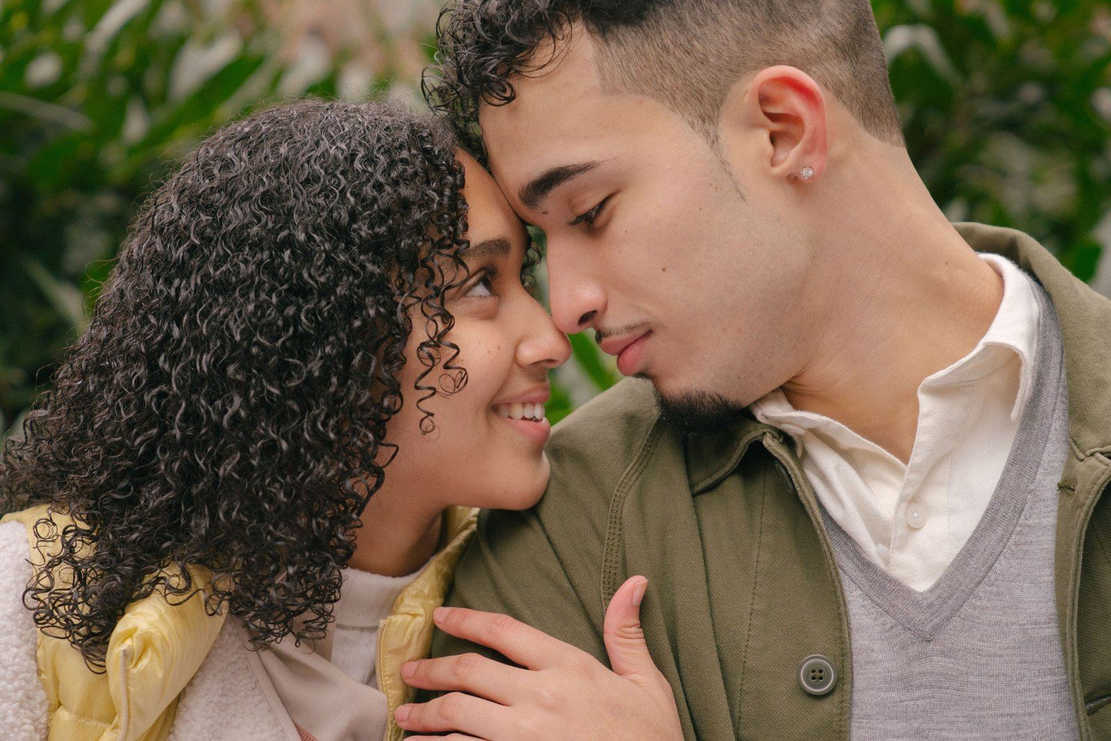 A couple standing close together outdoors, foreheads touching