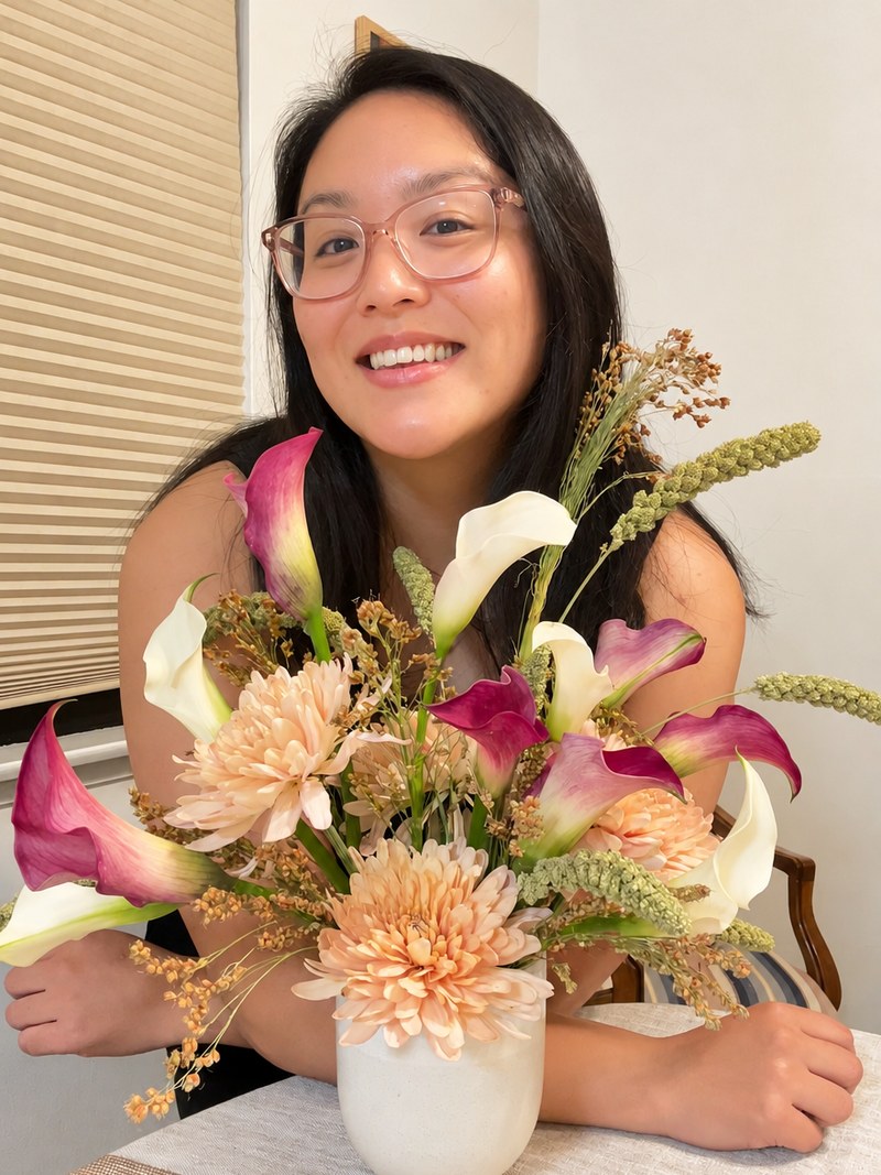 Stacy smiling behind a floral arrangement she made