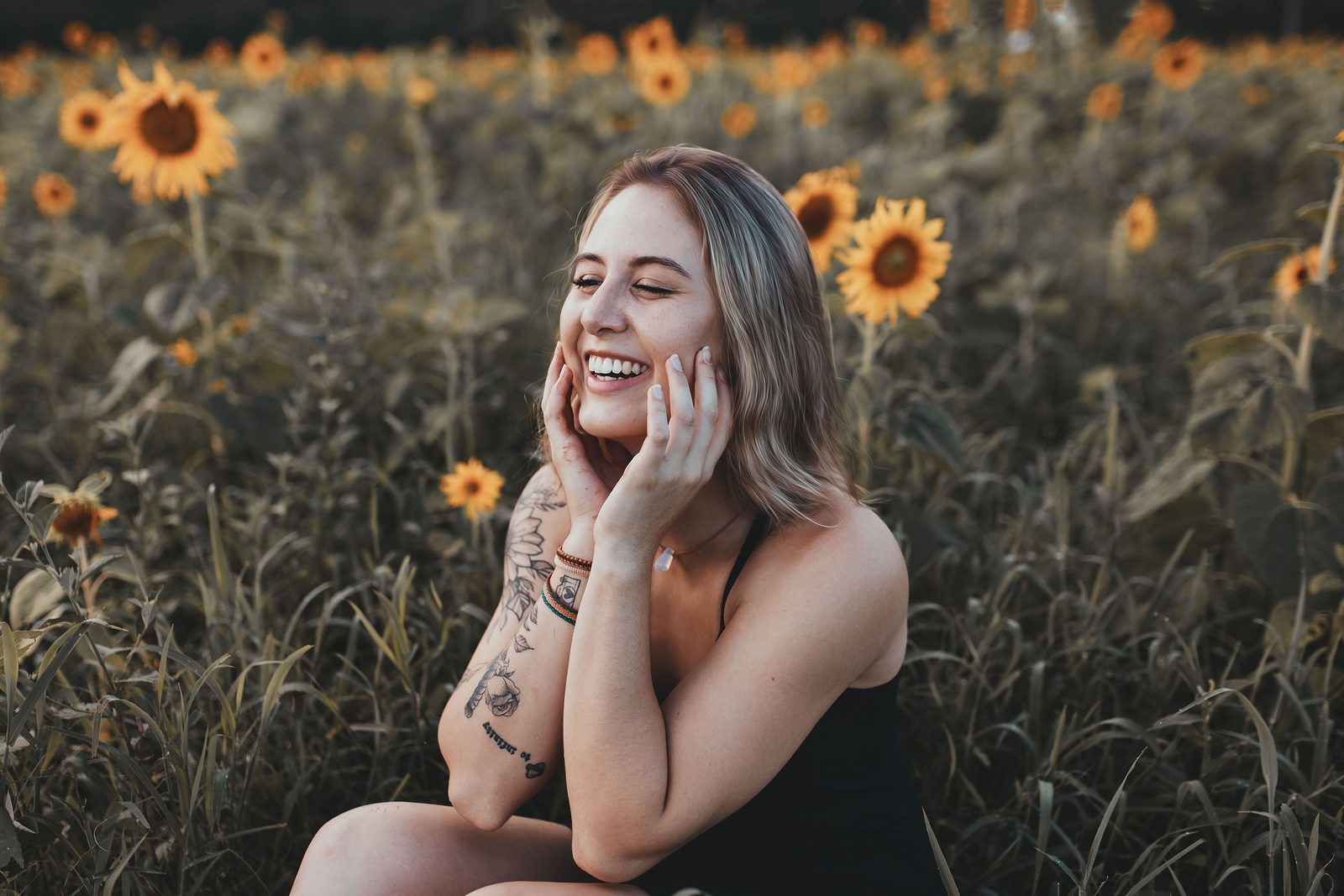 A woman smiling peacefully in a sunflower field, representing life beyond trauma